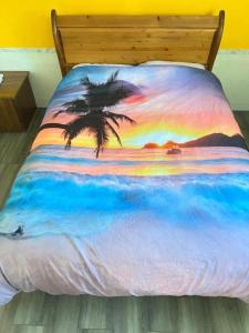 a bed with a painting of a beach with a palm tree at Surrey central in Surrey