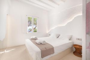 a white bedroom with a bed with towels on it at Sunset Cove in Agios Ioannis Mykonos