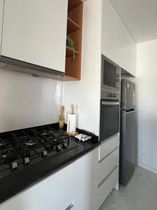 a kitchen with a stove top and a refrigerator at T3 Moderno e Confortável in Praia
