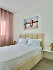 a bedroom with a large white bed with two people and a dog at T3 Moderno e Confortável in Praia