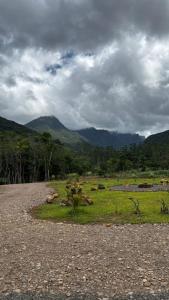 a gravel road with a field with mountains in the background at Sombra do baú -Luar in Timbe do Sul