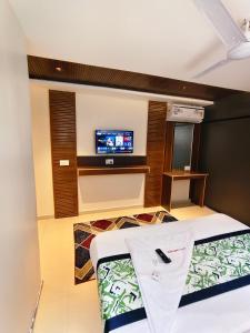 a room with a tv and a bed in a room at Hotel Gandharva Executive in Pune +8 photos