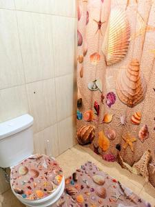 a bathroom with a toilet with a wall covered in shells at GuestHouse Encanto del Centro 2 in Encarnación