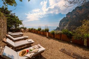 a row of lounge chairs with a view of the mountains at Villa Punta del Sole in Positano