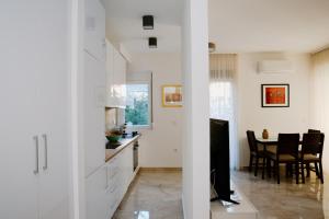 a kitchen and dining room with white cabinets and a television at Bellavista Garden in Baošići
