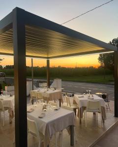 a restaurant with white tables and chairs with the sunset at Hotel-Ristorante KerMes in Boccaleone