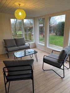 ein Wohnzimmer mit Sofa, Tisch und Fenstern in der Unterkunft Dejrupvej in Ovtrup