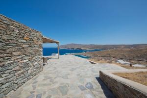 a stone walkway next to a stone wall with a bench at Stone Wave Kythnos in Loutra