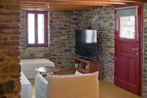 a living room with a tv and a red door at Stone Wave Kythnos in Loutra