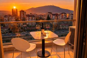 a table with two glasses of wine on a balcony at Capitоl Suites & Apartments in Skopje