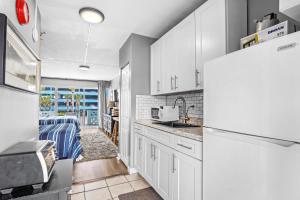 a kitchen with white cabinets and a refrigerator at Pool Front & Across from Beach in Myrtle Beach