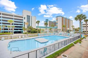 a swimming pool with palm trees and buildings at Pool Front & Across from Beach in Myrtle Beach