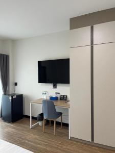 a room with a desk and a tv on a wall at AlinApartment in Ban Sa Kruat