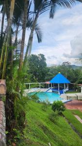 a swimming pool with a blue tent and palm trees at Finca Casa Real la Vega in La Vega