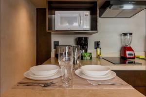 a kitchen counter with plates and glasses and a microwave at Bakal Luxury condos in Tulum +5 photos