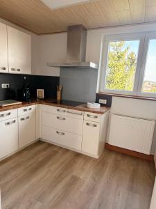 a kitchen with white cabinets and a large window at Cozy Home in Schramberg
