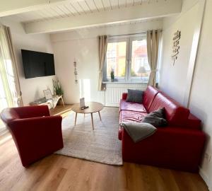 ein Wohnzimmer mit zwei roten Sofas und einem Tisch in der Unterkunft Kleine Ella Pellworm in Pellworm
