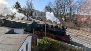 a steam train traveling down the tracks next to a street at Hotel Villa Fröhlich in Baabe
