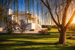 a large white house with a tree in the yard at Abaton - Casa vacanza in Metaponto