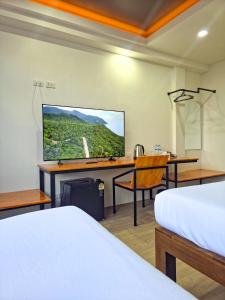ein Hotelzimmer mit einem Schreibtisch und einem Fernseher an der Wand in der Unterkunft SANDB Hotel in Ko Phangan
