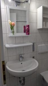 a bathroom with a sink and a mirror and flowers at Hotel Villa Fröhlich in Baabe +44 photos