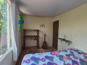 a bedroom with a bed and a guitar in it at Bela Oyá Casa Hostel in Vale do Capao +22 photos