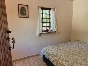 a bedroom with a bed and a window at Bela Oyá Casa Hostel in Vale do Capao