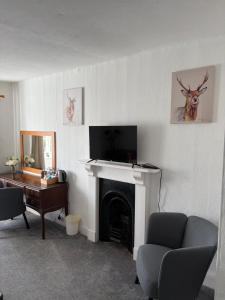 a living room with a fireplace with a tv at The Cleave Inn in Lustleigh