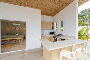 a kitchen with white countertops and a living room with a couch at Antemar Guest, Beach bungalow near Conchal in Brasilito
