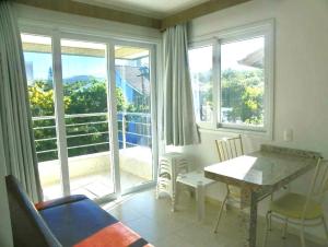 a living room with a table and chairs and a balcony at Villa Maciel Bombinhas in Bombinhas