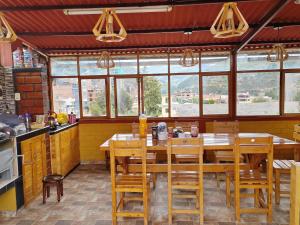 a kitchen with a wooden table and some windows at Alma Andina Lodge in Huaraz