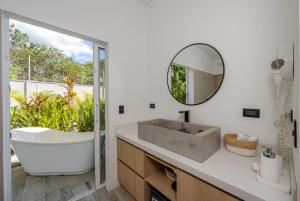 a bathroom with a tub and a sink and a mirror at Antemar Guest, Beach bungalow near Conchal in Brasilito
