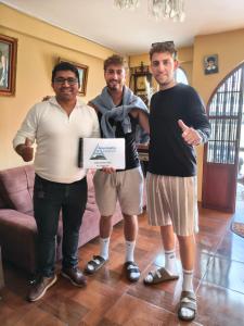 three men posing for a picture holding a box at Alma Andina Lodge in Huaraz
