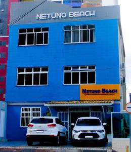 two cars parked in front of a blue building at Hotel Netuno Beach in Fortaleza