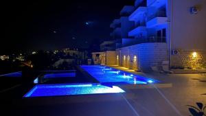 a pool with blue lights on a building at night at Bellavista Garden in Baošići