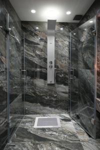 a bathroom with a shower with a stone wall at Djuric Apartmani in Zaječar +26 photos