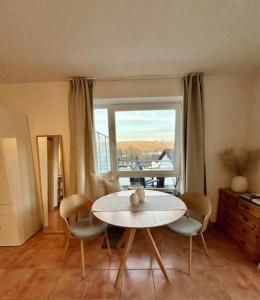 a living room with a table and chairs and a window at Modernes Studio mit Balkon & Seeblick am Biggesee in Olpe