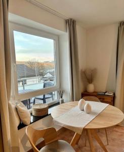 a living room with a table and a large window at Modernes Studio mit Balkon & Seeblick am Biggesee in Olpe