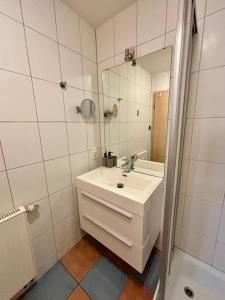 a white bathroom with a sink and a mirror at Modernes Studio mit Balkon & Seeblick am Biggesee in Olpe
