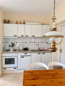 a kitchen with white cabinets and a table with chairs at AGAPI Holiday House in Vouníon