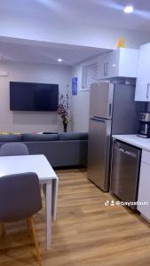 a kitchen and living room with a refrigerator and a table at Cozy Urban Hideout in Saskatoon