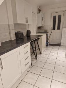 a kitchen with white cabinets and a black counter top at Leasowe House in Bidston