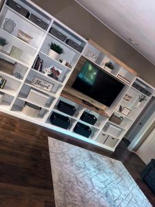 a living room with a tv and white shelves at Sugar Maple Getaway in Gaylord