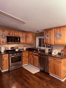 a kitchen with wooden cabinets and stainless steel appliances at Sugar Maple Getaway in Gaylord