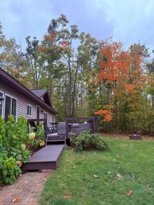 a yard with a house with a wooden deck at Sugar Maple Getaway in Gaylord