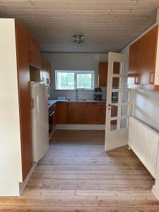 eine Küche mit Holzschränken und einem weißen Kühlschrank in der Unterkunft Dejrupvej in Ovtrup