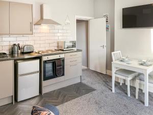 a kitchen with white cabinets and a table and a counter at Poppy - Uk49361 in Bridlington