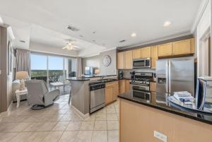 a kitchen with stainless steel appliances and a living room at Wharf 615 by Youngs Suncoast in Orange Beach