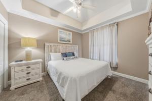 a bedroom with a white bed and a lamp and a window at Wharf 615 by Youngs Suncoast in Orange Beach