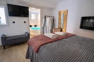 a bedroom with a bed with a chair and a mirror at Apartamentos De la Haya & Suite con Jacuzzi, junto al Teatro Romano in Mérida